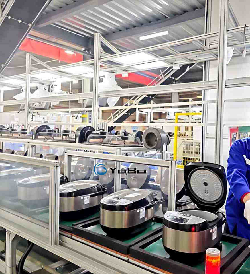 La olla arrocera es un pequeño electrodoméstico de cocina con una tasa de adopción muy alta en los hogares. Su ciclo de renovación es rápido y la demanda del mercado es enorme. Para lograr una producción estable y a gran escala de ollas arroceras, una **línea de montaje de ollas arroceras** con un buen ajuste al proceso es la base de hardware fundamental para cualquier fabricante. La línea de producción de ollas arroceras es un equipo de ensamblaje integral para electrodomésticos que integra el transporte de piezas, el montaje de máquinas completas, las pruebas de rendimiento multidimensionales, el envejecimiento con corriente y la clasificación y salida de productos terminados. Se adapta al ensamblaje en serie de distintos modelos, como ollas mecánicas y ollas arroceras inteligentes con control por placa, y ayuda a las fábricas de electrodomésticos de cocina a aumentar el ritmo de producción, unificar los criterios de montaje y reducir las variaciones de calidad causadas por la mano de obra.Toda la línea de montaje de ollas arroceras organiza sus puestos de trabajo siguiendo estrictamente el procedimiento de ensamblaje de la olla arrocera. El sistema de transporte principal utiliza cadenas de velocidad variable, junto con bandejas de herramientas específicas que soportan la olla interior y la carcasa durante todo el recorrido de la línea. El flujo de producción comienza con la carga de piezas y continúa con el posicionamiento de la olla interior, el montaje de la placa calefactora, la instalación de los componentes de control de temperatura, la conexión del arnés de cables interno, el ensamblaje del componente magnético, el montaje de la carcasa externa y la instalación del conjunto de la tapa. La línea de producción de ollas arroceras divide el ensamblaje complejo en una serie de operaciones estandarizadas; cada puesto tiene un alcance bien definido. Las bandejas de herramientas posicionan con precisión la carcasa de la olla, evitando golpes o desplazamientos durante el transporte y garantizando la estabilidad de las piezas semiterminadas. Las bandejas se pueden ajustar y reemplazar rápidamente, siendo compatibles con múltiples capacidades y estructuras de ollas arroceras en una misma línea. De esta manera, las empresas no necesitan construir una línea separada para cada modelo nuevo, lo que permite controlar la inversión en infraestructura. El puesto de pruebas es la etapa clave de la línea de montaje de ollas arroceras para garantizar la calidad de los productos terminados. La línea de producción de ollas arroceras incorpora varios puestos de prueba especializados. Cuando las unidades semiterminadas llegan al área de inspección, se realizan sucesivamente la comprobación de rendimiento eléctrico, la verificación de la potencia de la placa calefactora, la prueba de control de temperatura y la inspección de seguridad de aislamiento. El módulo de prueba eléctrica verifica la placa de control principal, la placa calefactora, el termostato magnético y el sensor de temperatura, detectando conexiones defectuosas, componentes dañados o errores de cableado. La prueba de potencia mide la potencia real de trabajo de la placa calefactora para confirmar que los parámetros de salida cumplen con el diseño. La prueba de temperatura simula las condiciones de cocción para validar la lógica de control térmico. La prueba de resistencia de aislamiento realiza la verificación de seguridad eléctrica, evitando riesgos de fuga de corriente. Los productos defectuosos detectados se marcan y se desvían al área de reparación, evitando que piezas semiterminadas con fallos avancen a los procesos siguientes. Las unidades que pasan la inspección entran en la zona de envejecimiento, donde permanecen encendidas durante un tiempo prolongado simulando condiciones reales de cocción. Esto permite detectar de forma temprana fallos iniciales de los componentes y reducir la tasa de fallos en el mercado final. La línea de producción de ollas arroceras se diseña con estructura modular. Las bandas transportadoras pueden configurarse en disposición recta o en bucle cerrado según las condiciones de espacio de la planta, siendo aptas tanto para nuevos proyectos de fábricas de electrodomésticos de cocina como para la actualización de plantas existentes. La línea incorpora cilindros de bloqueo y mecanismos de posicionamiento de parada, que garantizan la detención precisa de las bandejas de herramientas y facilitan el montaje manual y la conexión con equipos de inspección automática. Toda la línea de montaje de ollas arroceras está equipada con un sistema de control eléctrico centralizado que muestra en tiempo real el ritmo de operación, el estado de cada puesto, los recuentos de producción y las alarmas de fallos. Los gestores de producción pueden consultar los datos de fabricación en cualquier momento para calcular la capacidad, organizar la producción y resolver fallos de forma rápida. Los componentes de transmisión y eléctricos son de grado industrial, compatibles con la producción continua e ininterrumpida. El equipo es fácil de desmontar para mantenimiento, y el personal técnico de la planta puede realizar de forma independiente el mantenimiento rutinario y la reparación de fallos, reduciendo los costos operativos posteriores. En comparación con el trabajo manual disperso tradicional, la implementación de la línea de montaje de ollas arroceras permite optimizar la asignación de personal. Los procesos de ensamblaje se estandarizan, reduciendo los requisitos de cualificación de los puestos; el personal nuevo puede adaptarse rápidamente a sus tareas. Las bandejas de herramientas unificadas y el trabajo en línea eliminan las diferencias individuales causadas por la operación manual, garantizan la consistencia de calidad de cada olla arrocera y mejoran la tasa de productos conformes. La capacidad de producción de la línea de producción de ollas arroceras se configura según las necesidades del cliente: existen opciones desde líneas pequeñas y medianas hasta líneas de producción de gran escala, adecuadas tanto para fábricas pequeñas y medianas de electrodomésticos de cocina como para los requisitos de producción masiva de grandes empresas de electrodomésticos. En la actualidad, la competencia en el sector de pequeños electrodomésticos de cocina es intensa. La eficiencia productiva y la consistencia del producto son barreras competitivas importantes para los fabricantes. Una línea de montaje de ollas arroceras de alto rendimiento no es solo un equipo de transporte de piezas, sino una plataforma productiva que integra todo el ciclo: montaje, pruebas, envejecimiento y salida de productos terminados. Ayuda a los fabricantes de ollas arroceras a lograr una producción estandarizada en serie, acortar los ciclos de fabricación, controlar la calidad de los productos en todo el proceso, elevar el nivel general de manufactura de la planta y construir una ventaja competitiva en producción.